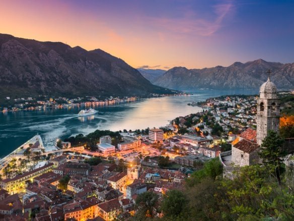 Montenegro river valley with historic town and mountains at sunset.