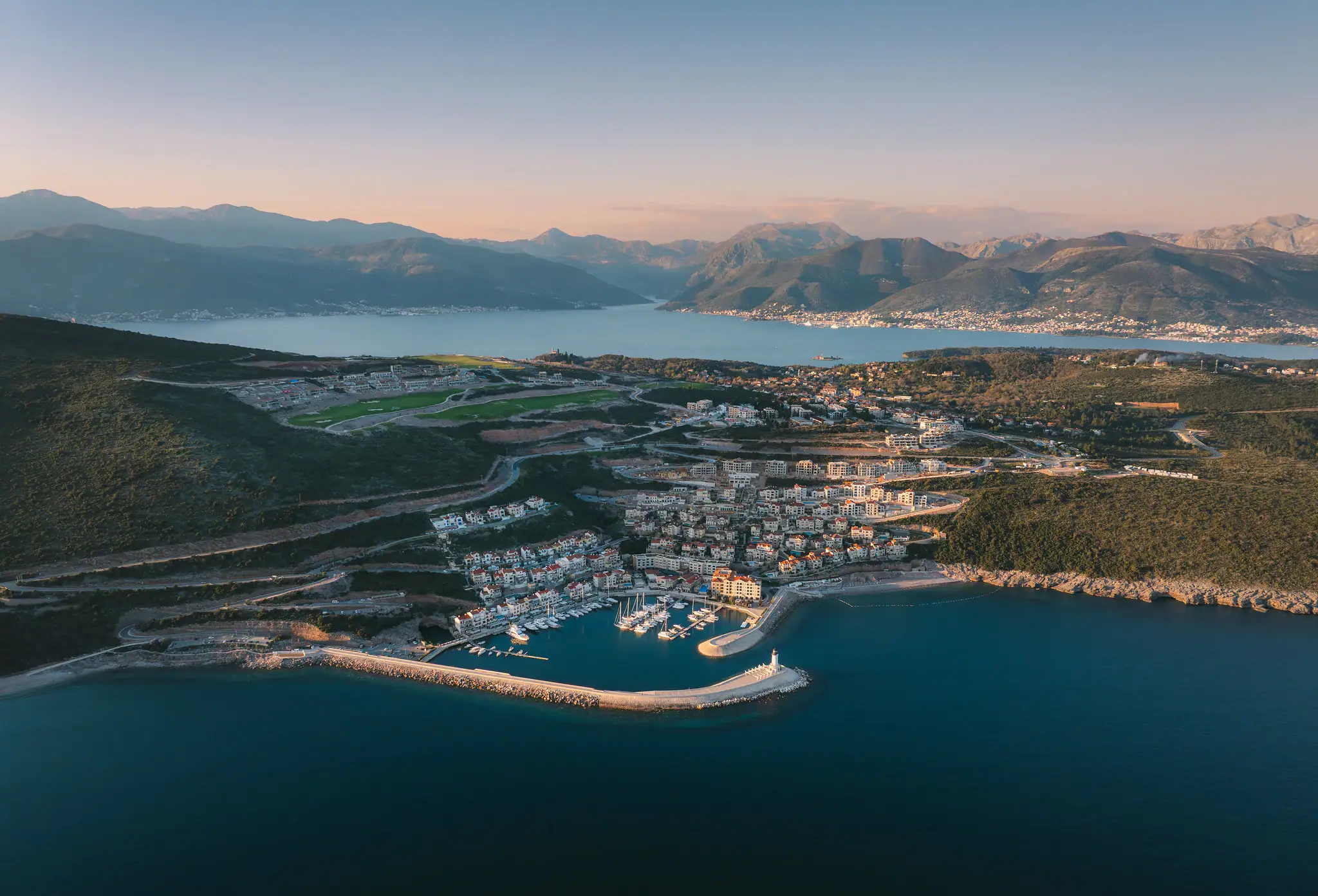 Aerial view of a luxury waterfront real estate development in Greece with mountains and sea.