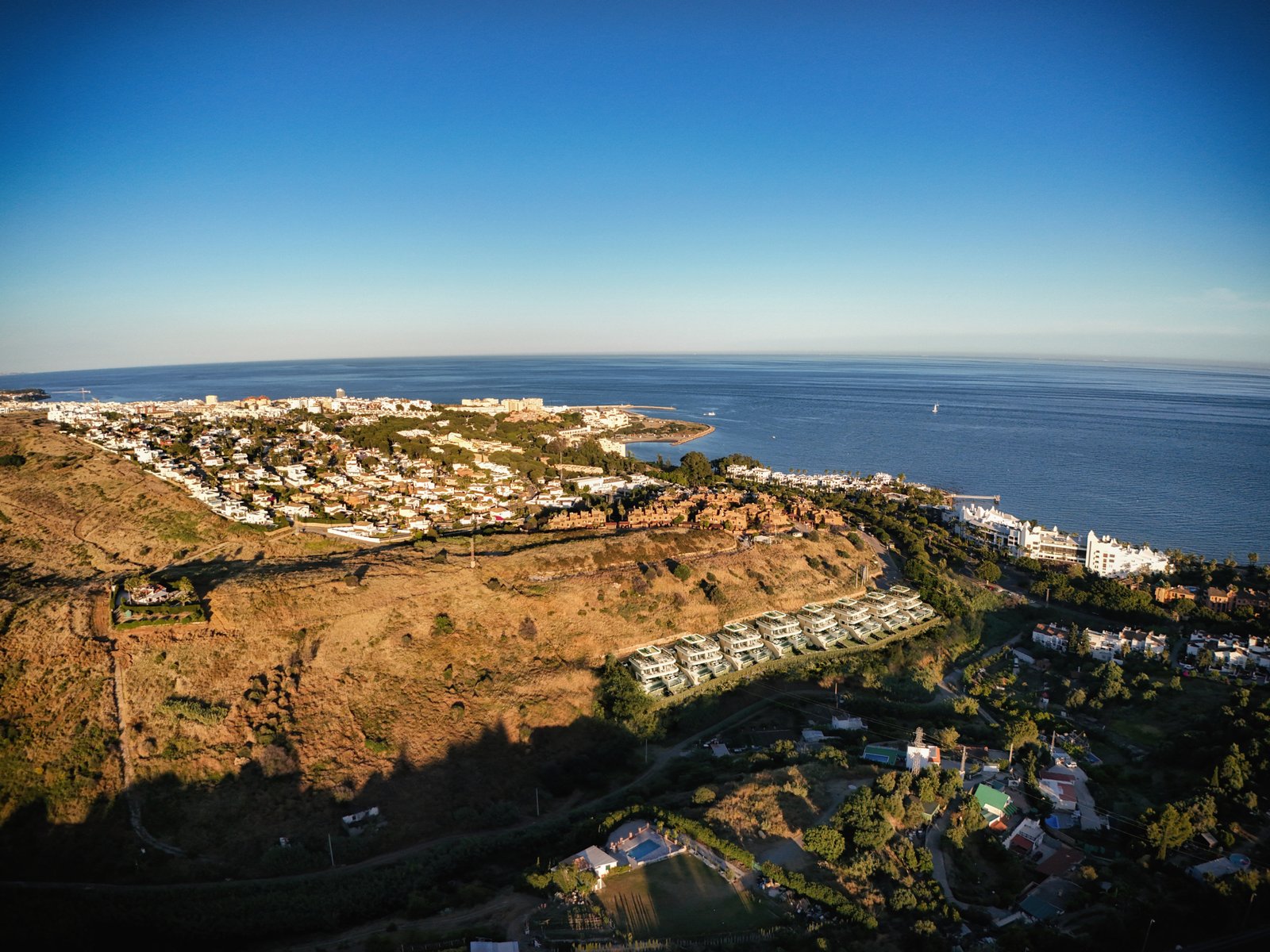 Scenic aerial view of Estepona's coast, hills, and residential areas near the sea.