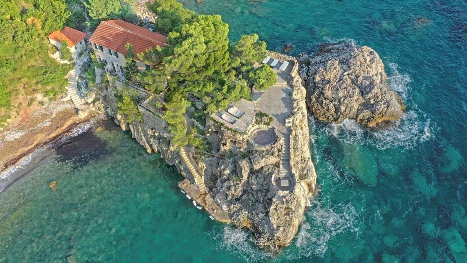 Luxury Montenegro estate on rocky coastline with lush greenery and panoramic sea views.