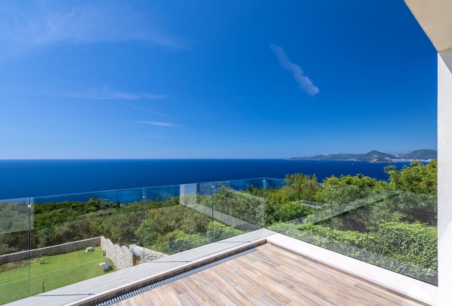 إطلالة بانورامية على البحر من فيلا فاخرة في مونتينيغرو، تطل على الخليج المفتوح والمساحات الخضراء المورقة.