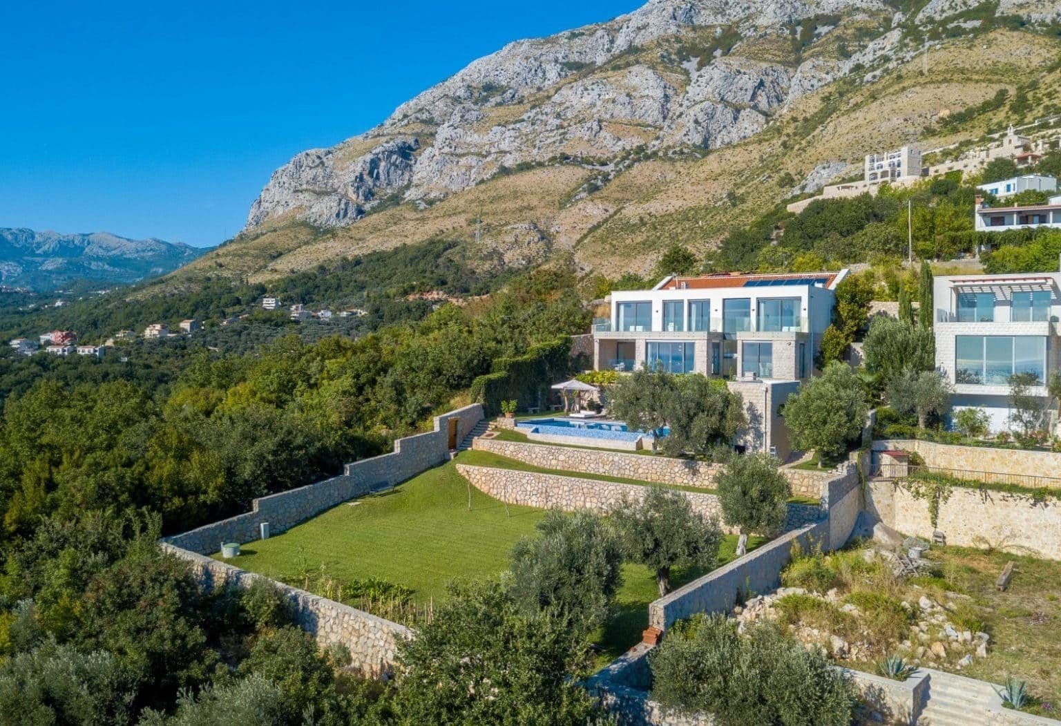 فيلا فاخرة تطل على مناظر بانورامية للخليج في مونتينيغرو، تتميز بتصميم معماري عصري ومساحات خضراء غناءة.