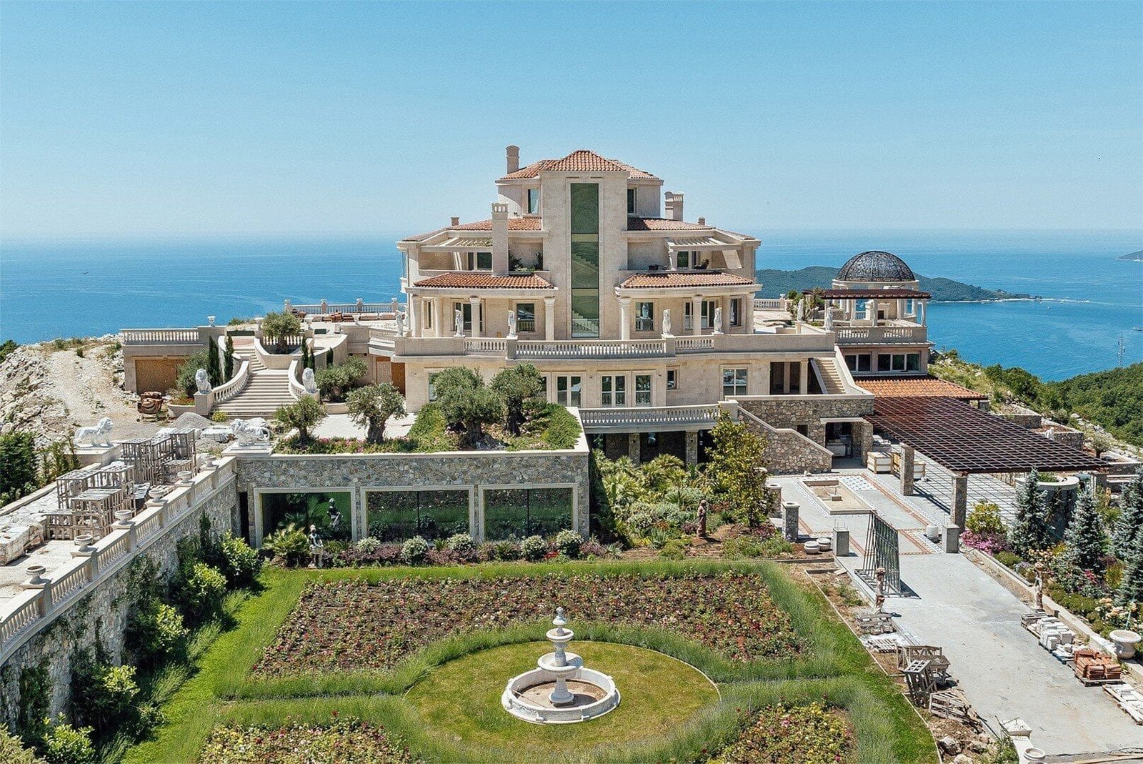 Opulent mansion overlooking the ocean, featuring expansive terraces and lush gardens.