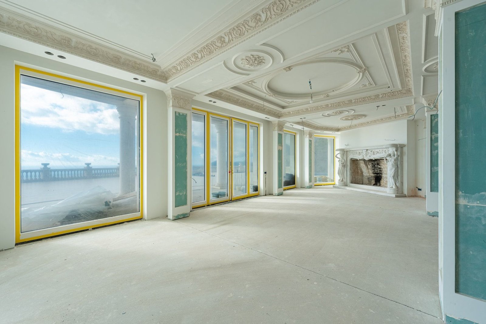 Spacious room with large windows offering stunning ocean views, ornate ceiling details, and elegant.
