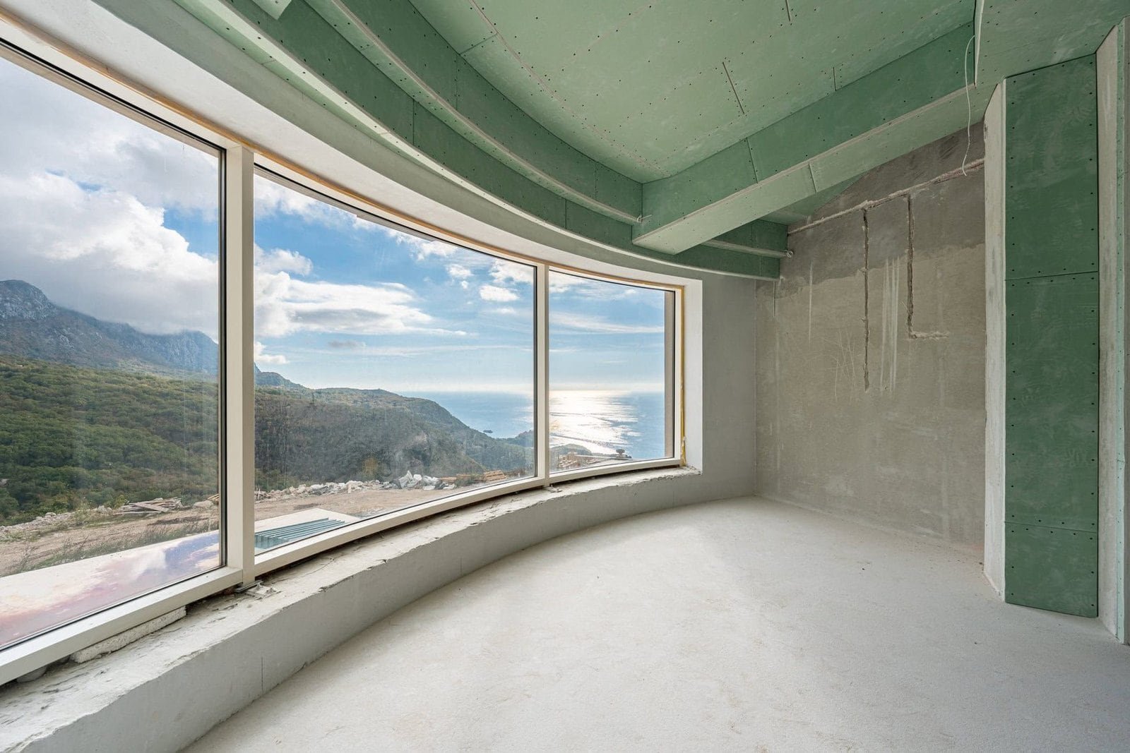 Panoramic ocean view from a modern coastal property with large curved windows and scenic mountain ba.