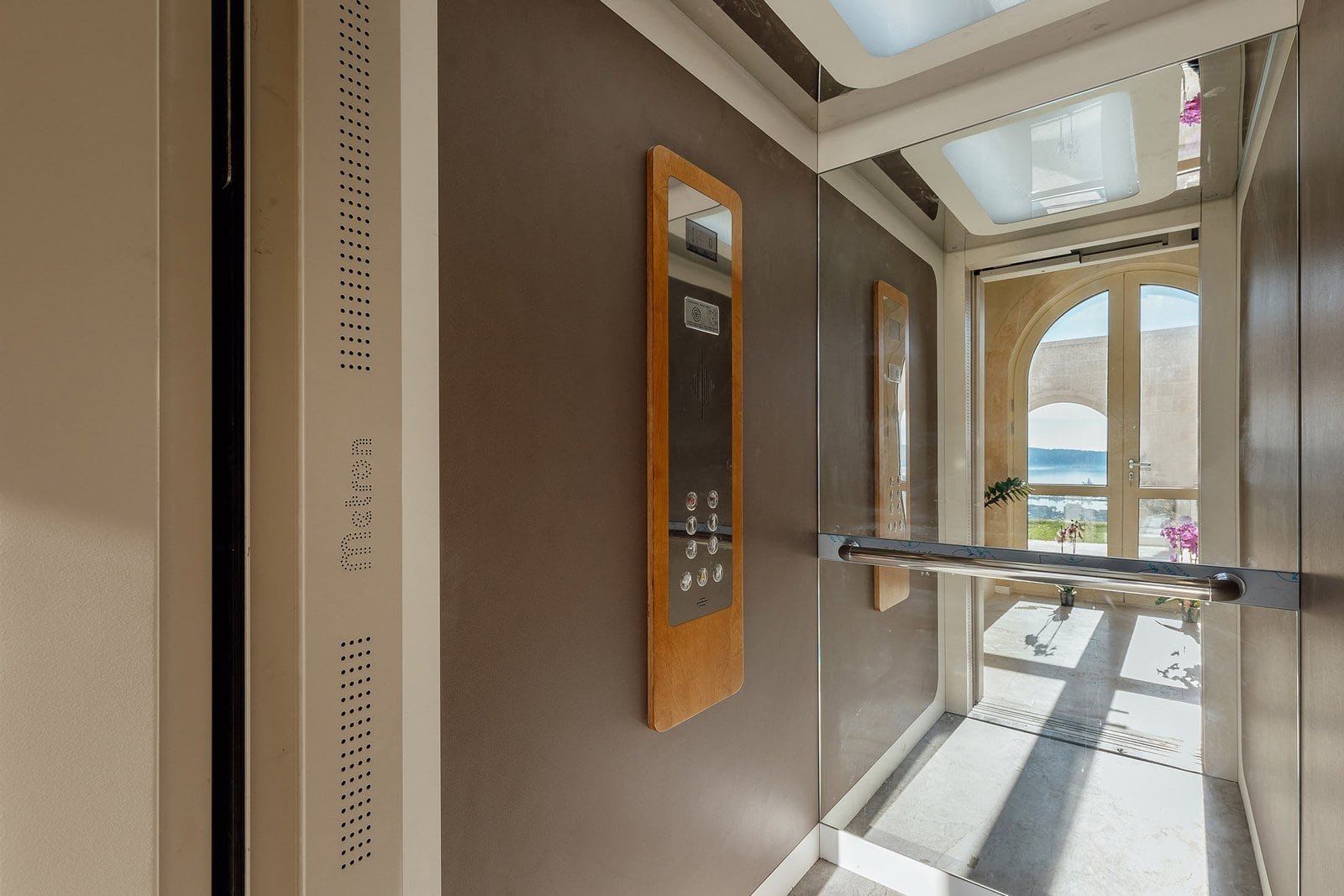 Modern elevator interior with scenic view and natural light, showcasing luxury property amenities.