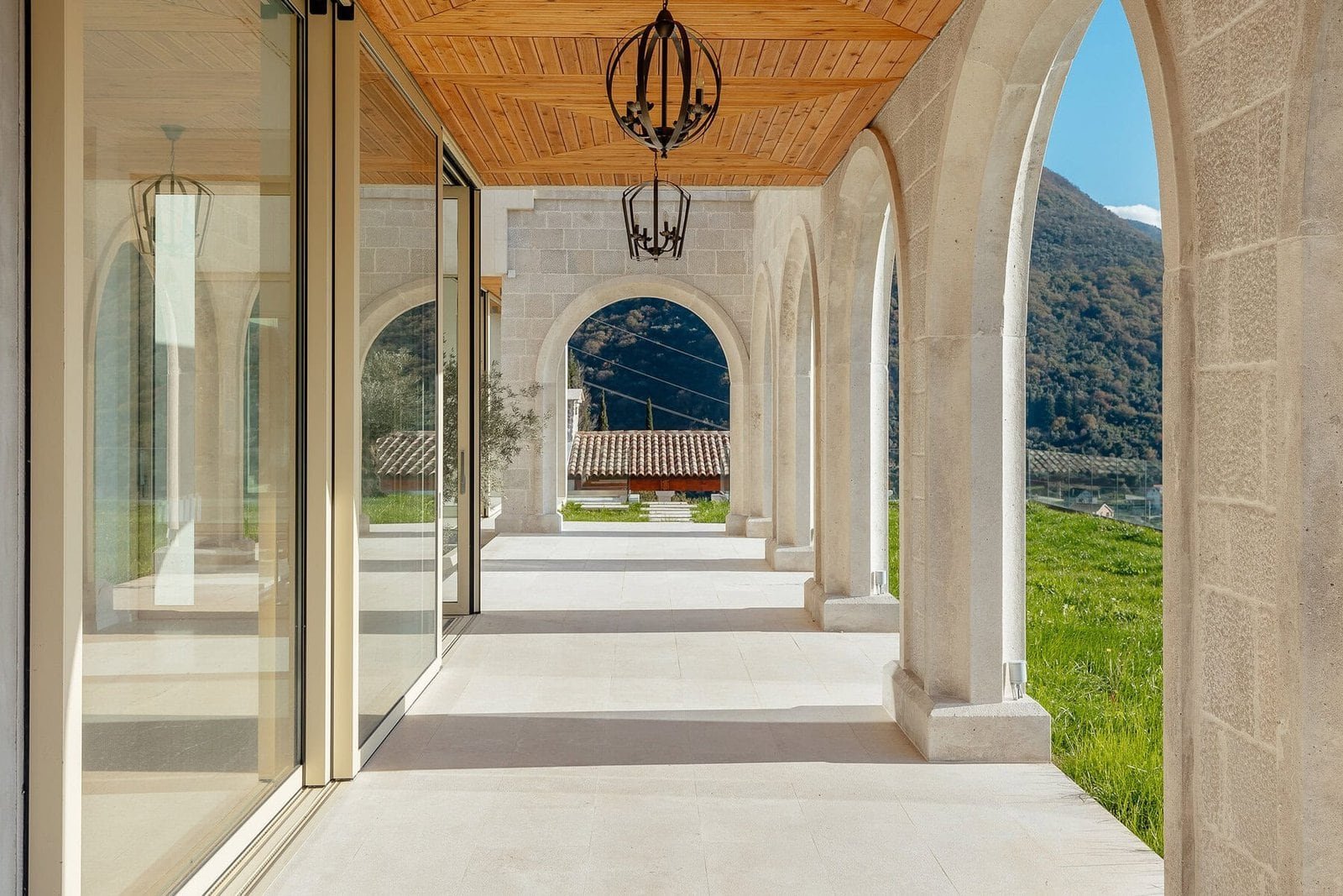 Elegant villa porch with arches, stone columns, and mountain scenery in the background.