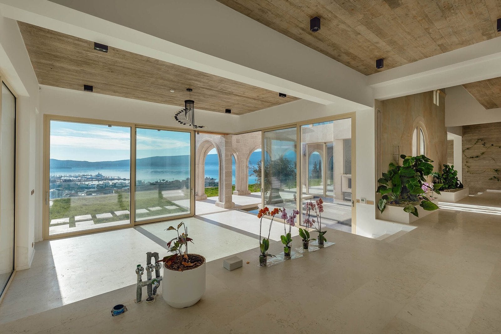 Modern interior with large glass windows showcasing stunning ocean and city views.