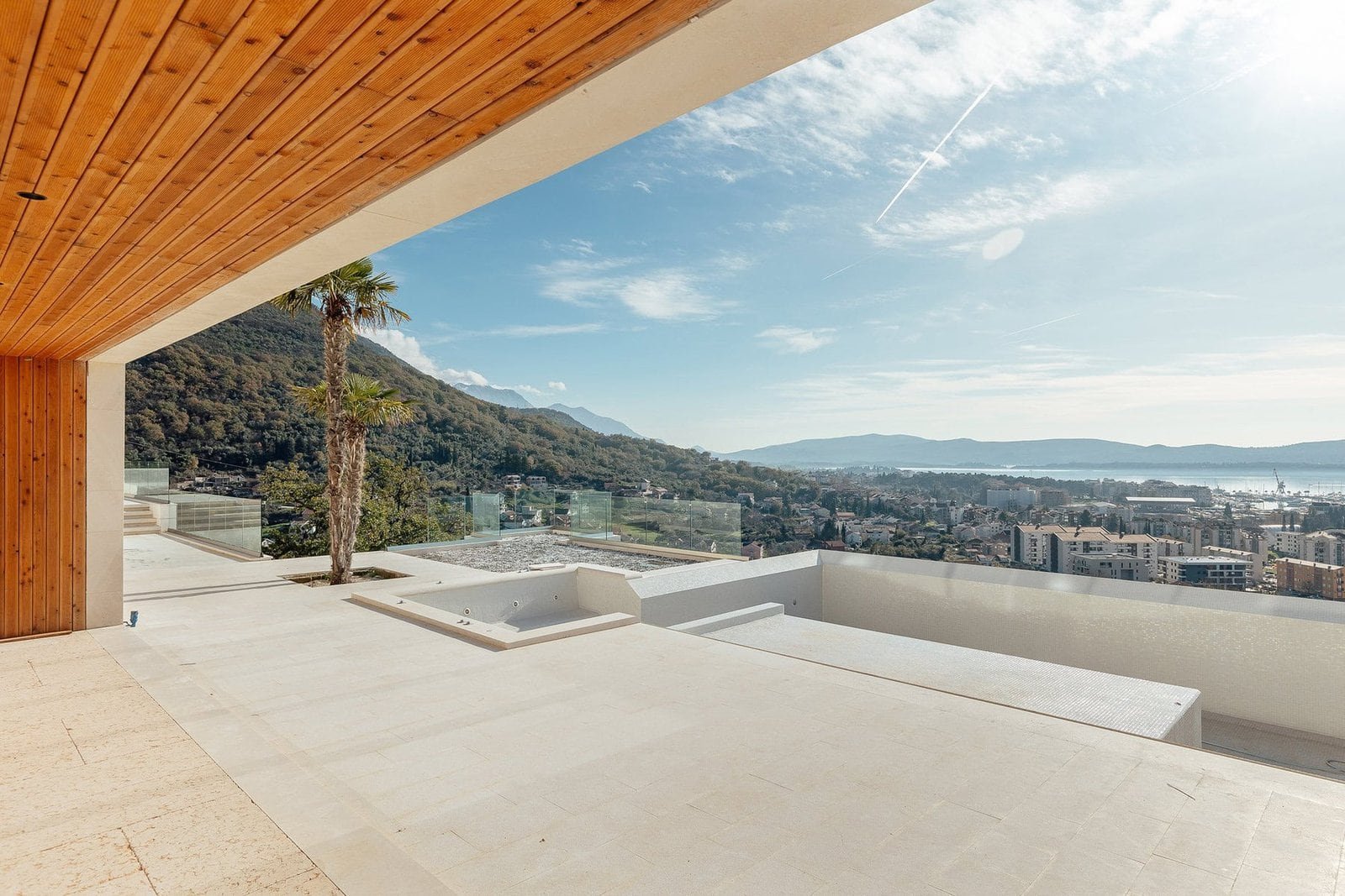Modern rooftop terrace overlooking cityscape and mountains with clear blue sky.