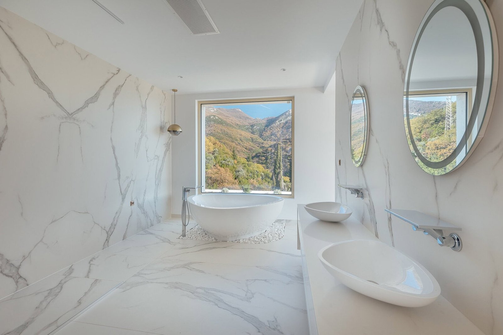 Luxury bathroom with mountain view, modern design, marble walls, and fixtures.