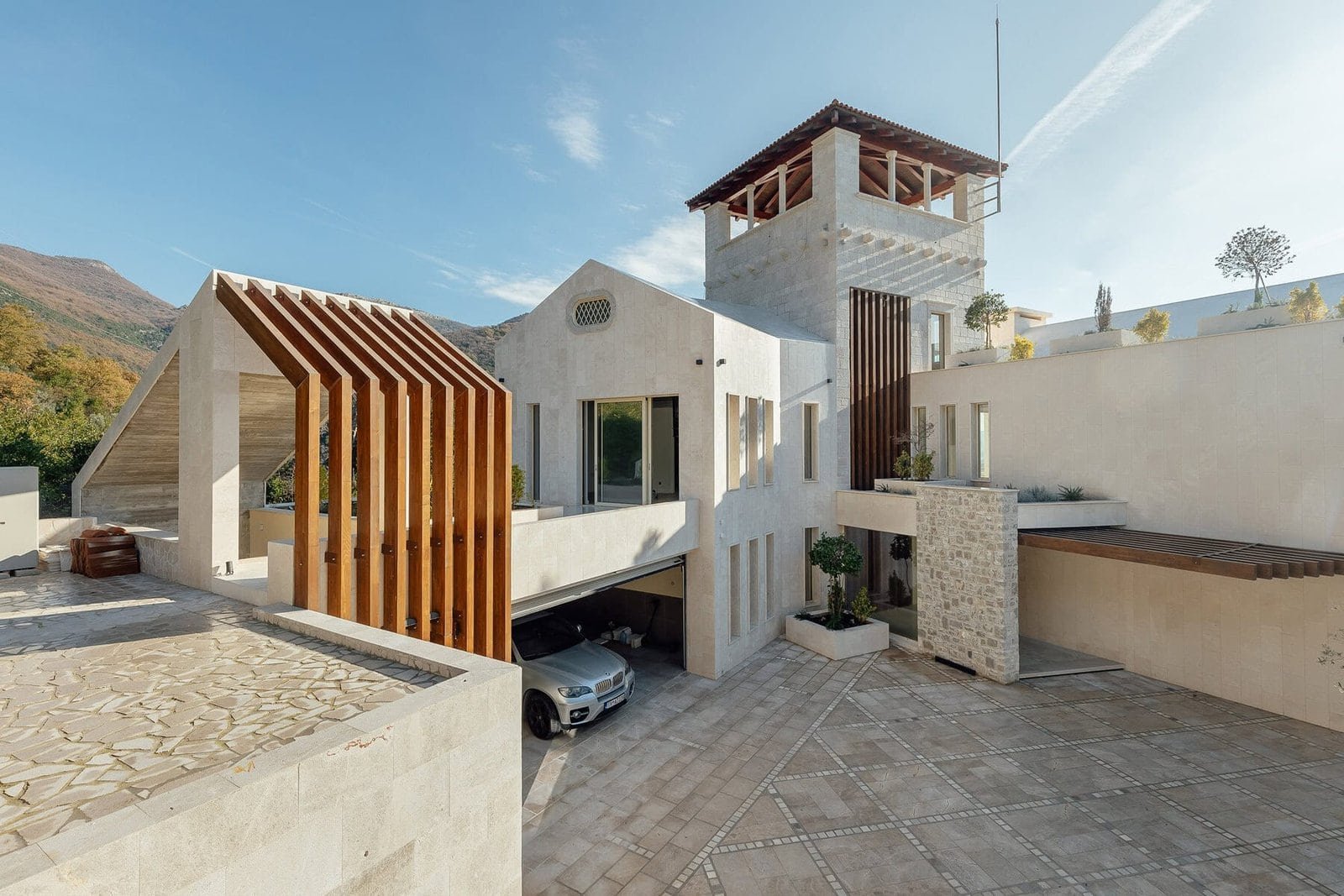 Elegant luxury villa with white walls, wooden features, and scenic mountain views.