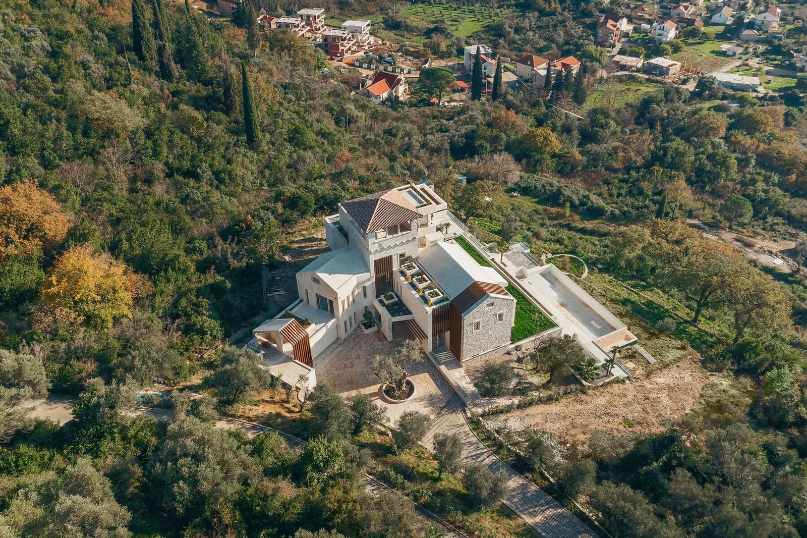 Aerial view of a luxury modern villa surrounded by lush greenery and trees near Barok Estates.