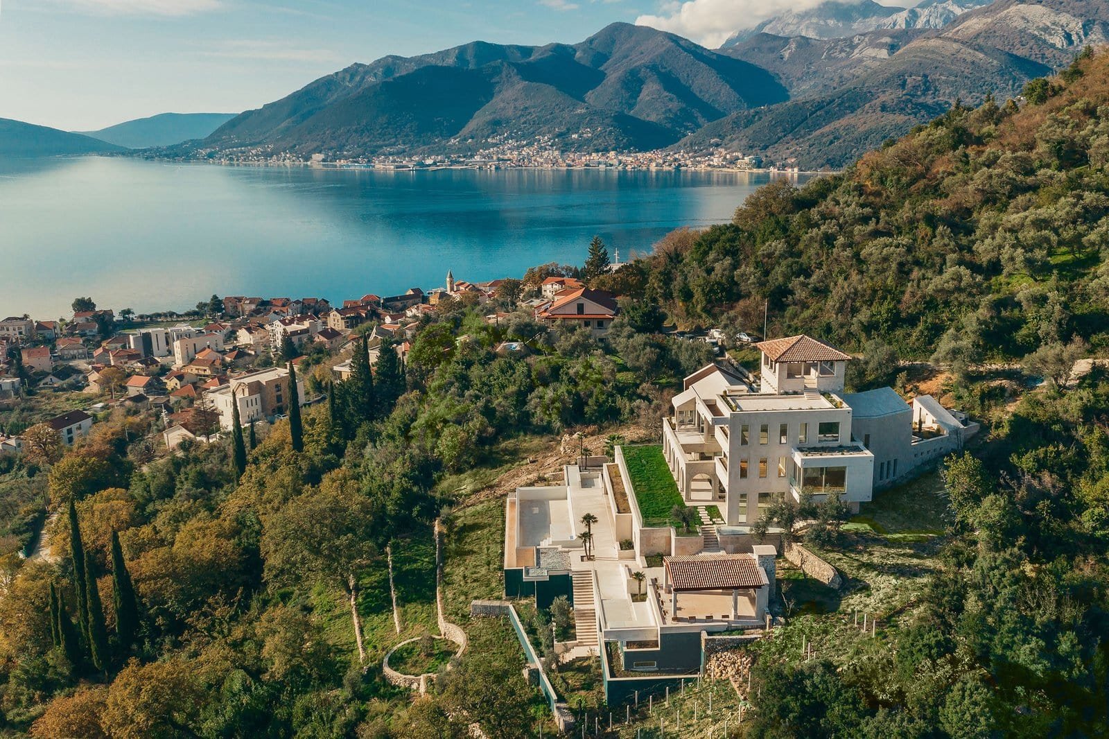 Stunning luxury villa overlooking a serene lake and lush mountains, perfect for exclusive real estat.