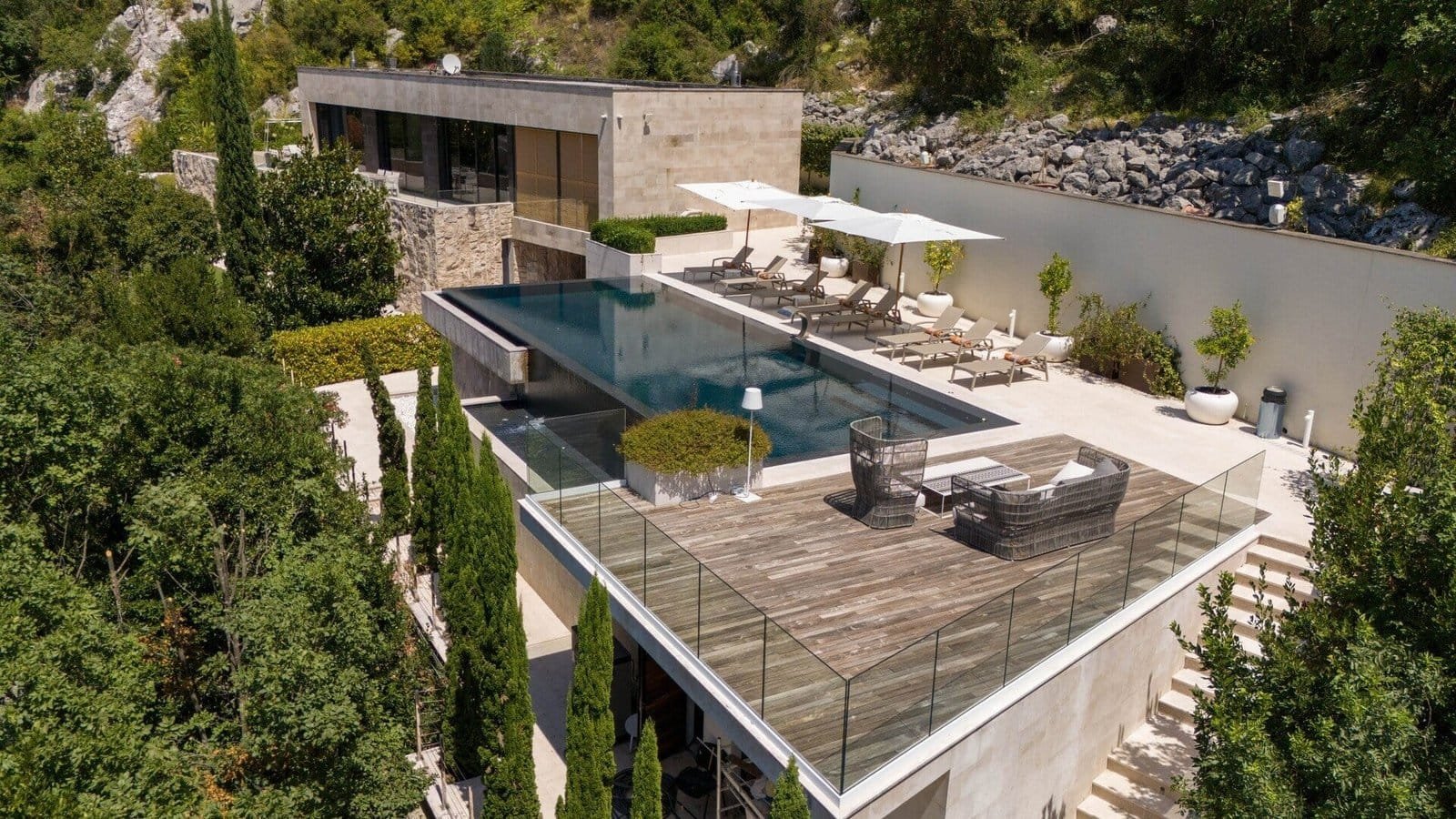 Modern luxury villa with infinity pool, outdoor terrace, and lush greenery surroundings.