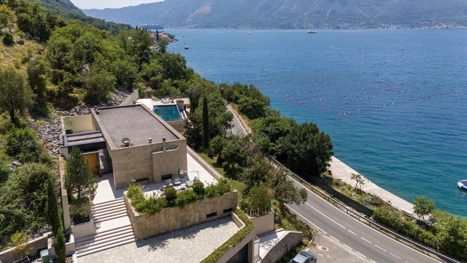 Modern seaside villa overlooking the ocean with lush greenery and terraced gardens.