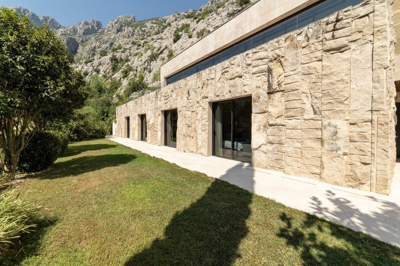 Elegant contemporary architecture with natural stone facade and large glass windows.