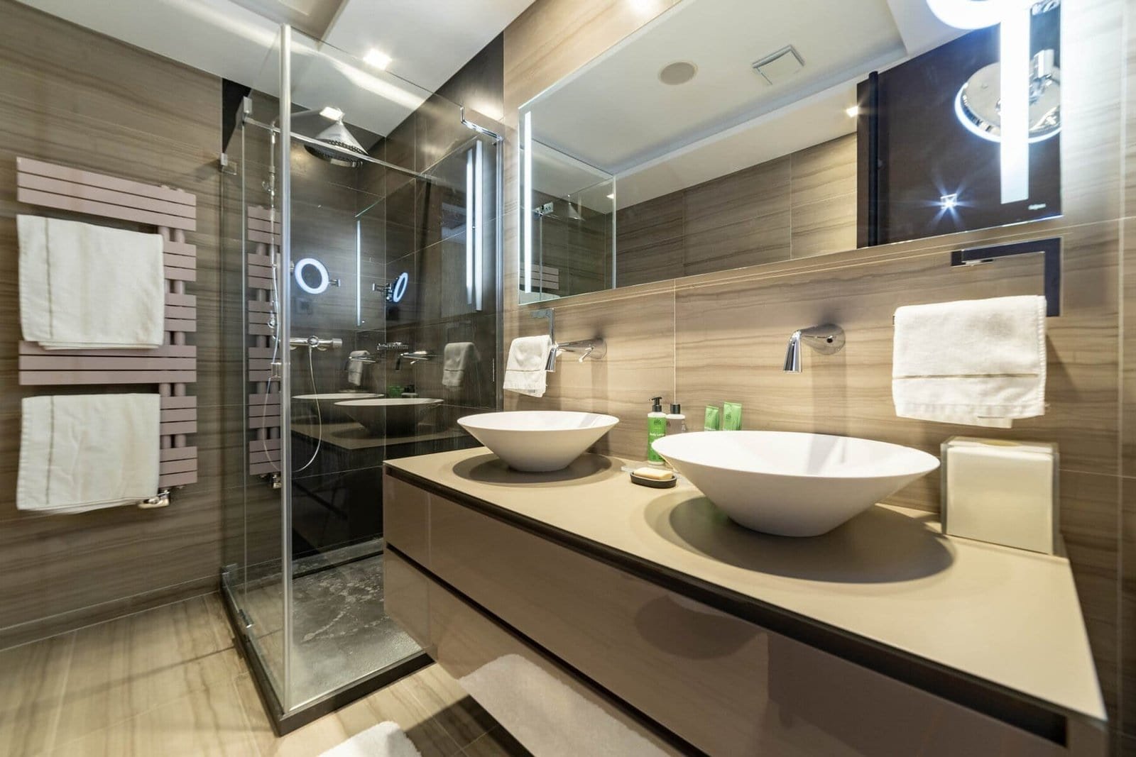 Luxury bathroom with double vessel sinks and glass shower.