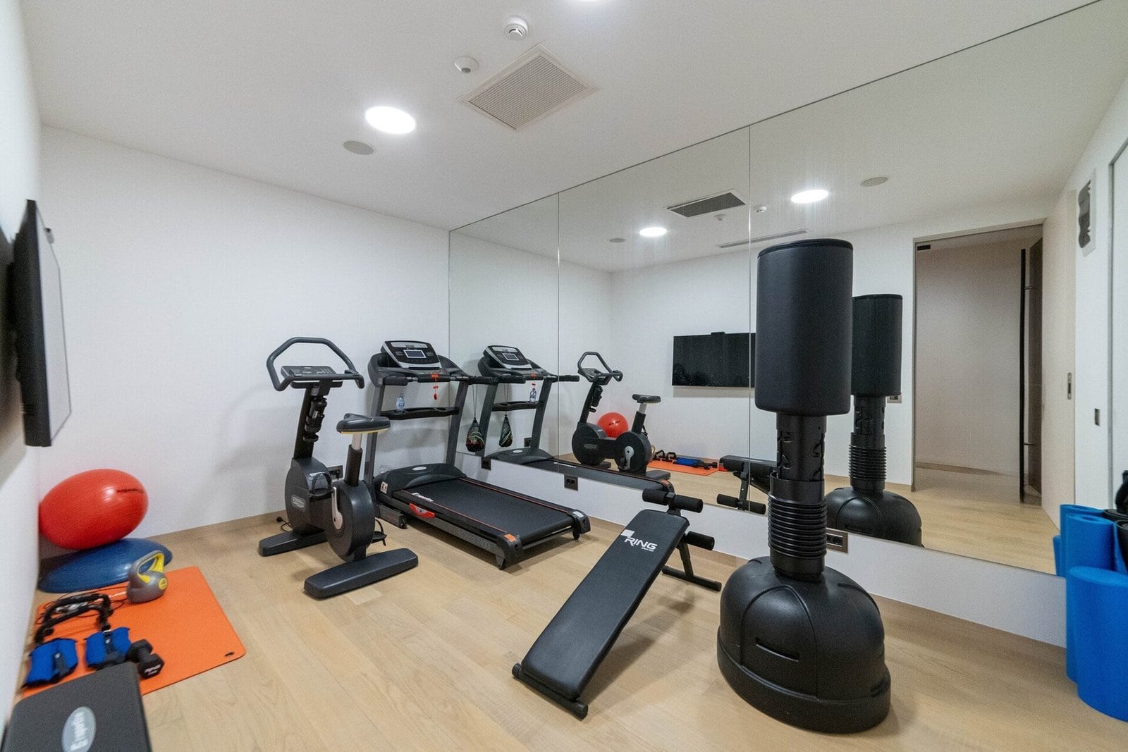 Home gym with treadmill, punching bag, and weights for effective workouts.