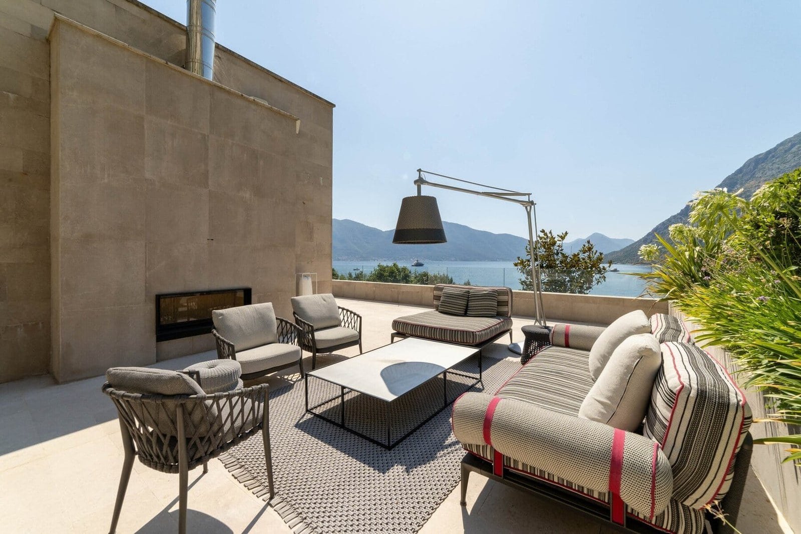 Luxury outdoor terrace with seating and scenic mountain and water views.