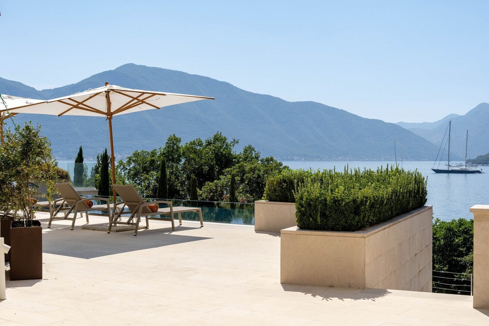 Luxury lakeside villa with scenic mountain views, outdoor pool, and relaxing sun loungers. Perfect f.