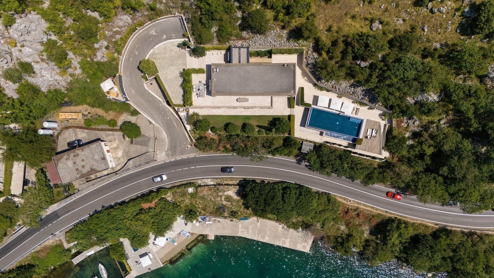 Aerial view of a luxurious villa featuring a private pool, surrounded by lush greenery and scenic la.