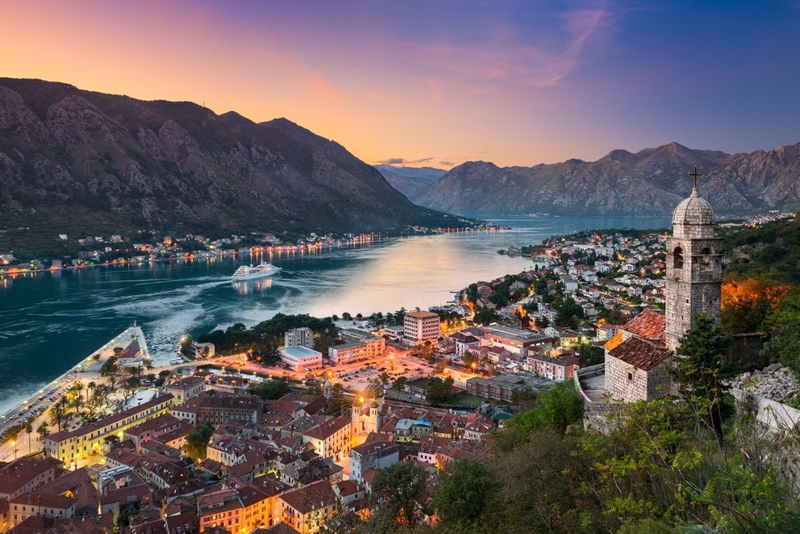 Montenegro river valley with historic town and mountains at sunset.