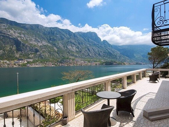 Waterfront stone villa balcony overlooking Boka Bay in Montenegro, with scenic mountain views and ou.