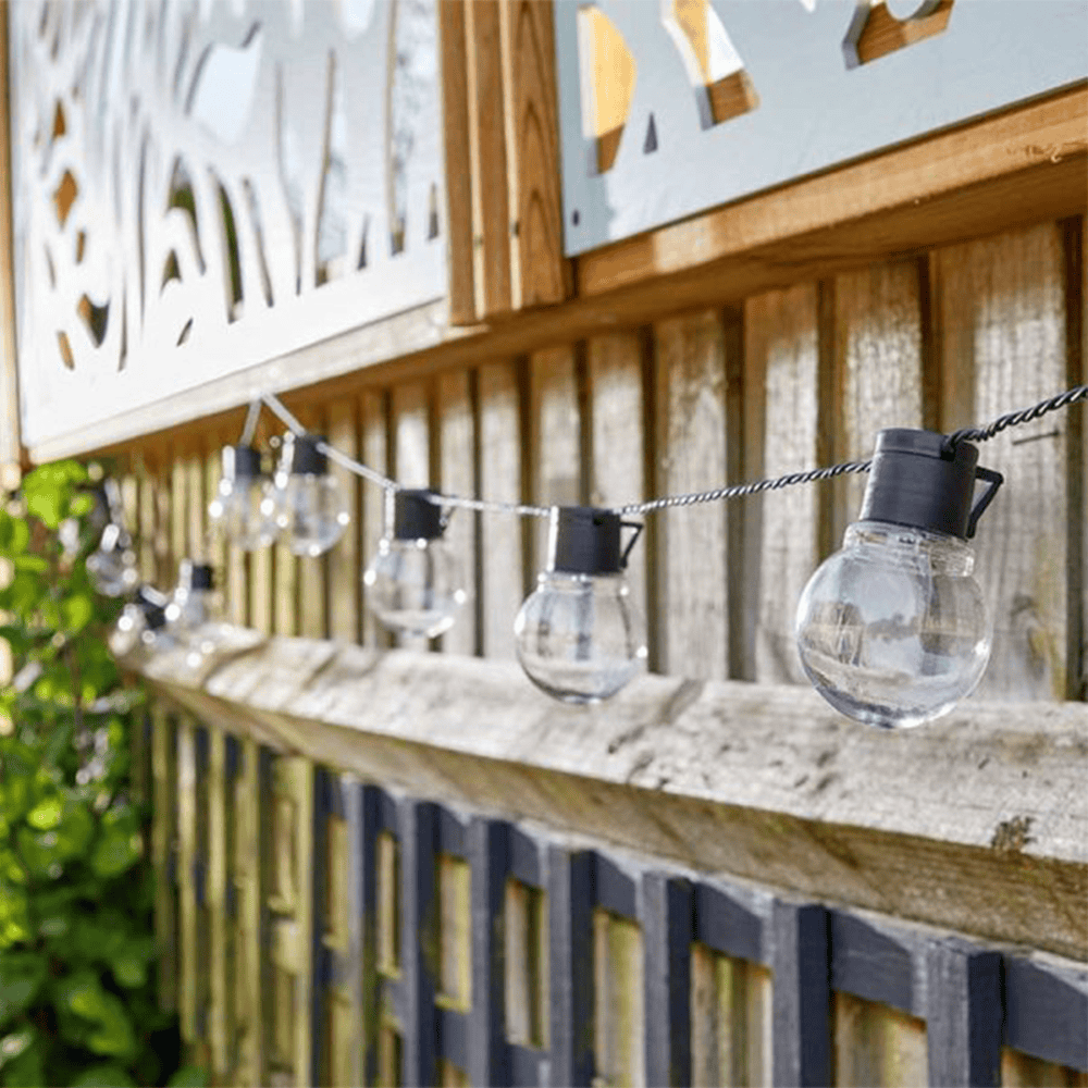 String of decorative outdoor solar light bulbs on a garden fence, ideal for garden lighting at Bayton Horticulture Centre.