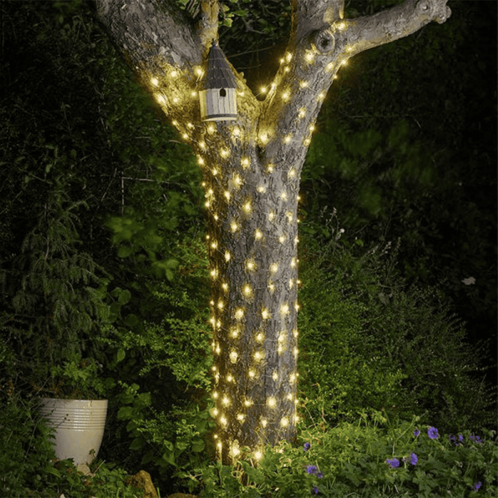 Twinkling fairy lights on garden tree for festive outdoor decor.