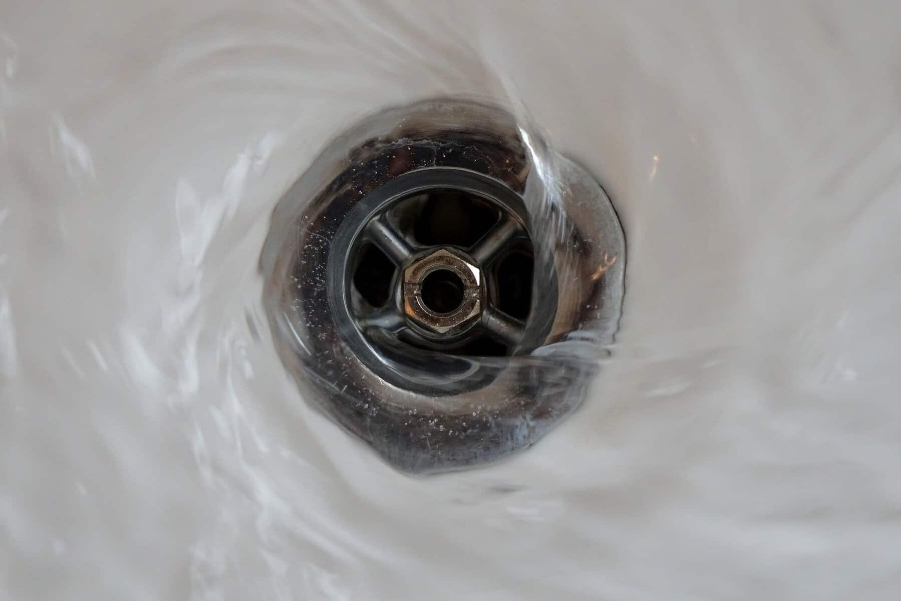 Close-up of water swirling down a metal sink drain, symbolizing the peace of mind Black Diamond Experts bring to every home repair.