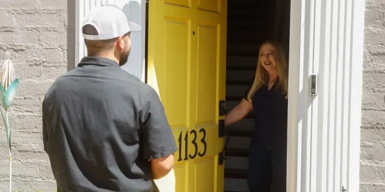 A welcoming homeowner opens a bright yellow door for a trusted Black Diamond Experts technician, ready to provide reliable repair service.