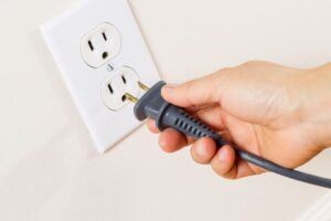 A hand carefully readies a power plug for the outlet—trust Black Diamond Experts for safe, reliable 24/7 home electrical care.