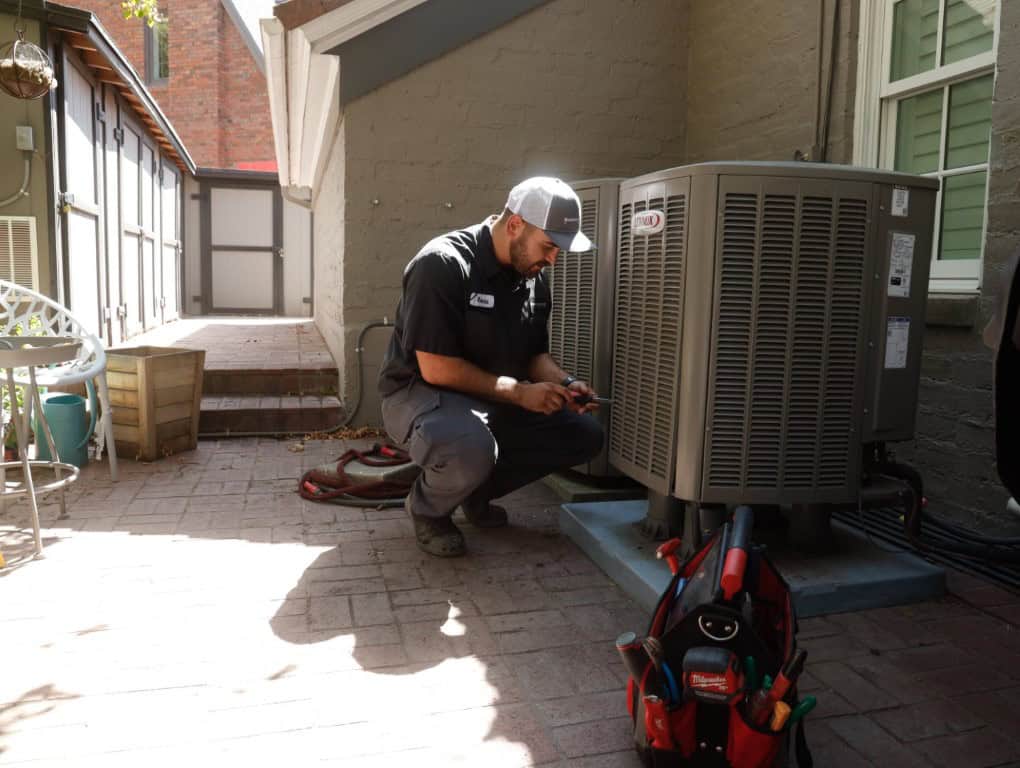A Black Diamond Experts technician services an outdoor AC unit with care, tools in hand—Utah’s trusted 24/7 home comfort pros.