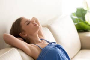 Woman in a blue top relaxes peacefully on a white couch, confident in Black Diamond Experts’ trusted 24/7 home comfort services.