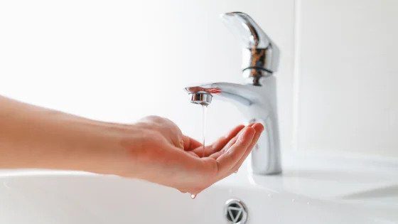 A hand beneath a bathroom faucet enjoys a steady stream of water—Black Diamond Experts deliver safe, reliable home services 24/7.