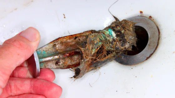 A skilled hand removes a clogged drain stopper, reflecting expert, reliable plumbing care provided 24/7 by Black Diamond Experts.