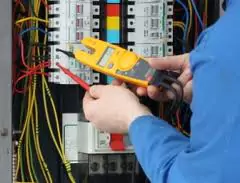 A skilled technician expertly checks circuit breaker wiring with a digital multimeter, ensuring your home's safety and comfort 24/7.