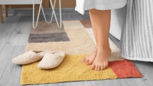A multicolored bathroom throw rug on the floor with a woman standing on it