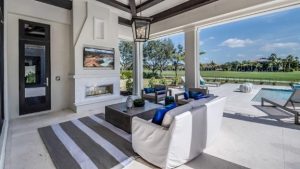 A furnished open patio with a swimming pool and overlooking a garden with trees