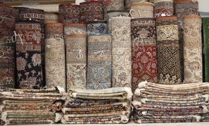 Variety of Persian rugs are rolled and stacked.