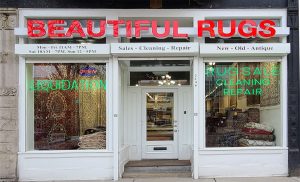 Store front of Beautiful Rugs with store signs and windows.
