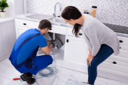 Technician repairing plumbing under kitchen sink at Blue Box Self Storage.