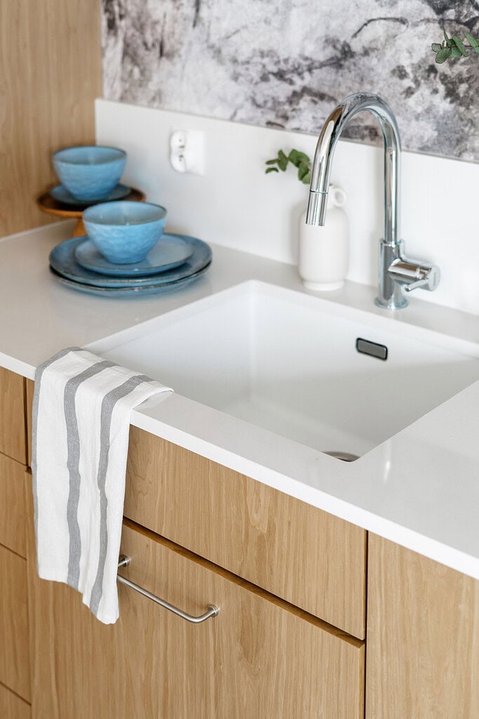 Modern kitchen sink with wooden cabinets and blue bowls, clean and stylish.