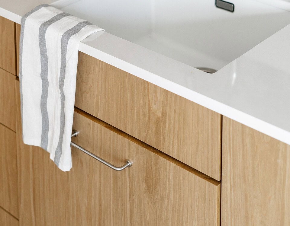Modern kitchen sink with wooden cabinets and blue bowls, clean and stylish.