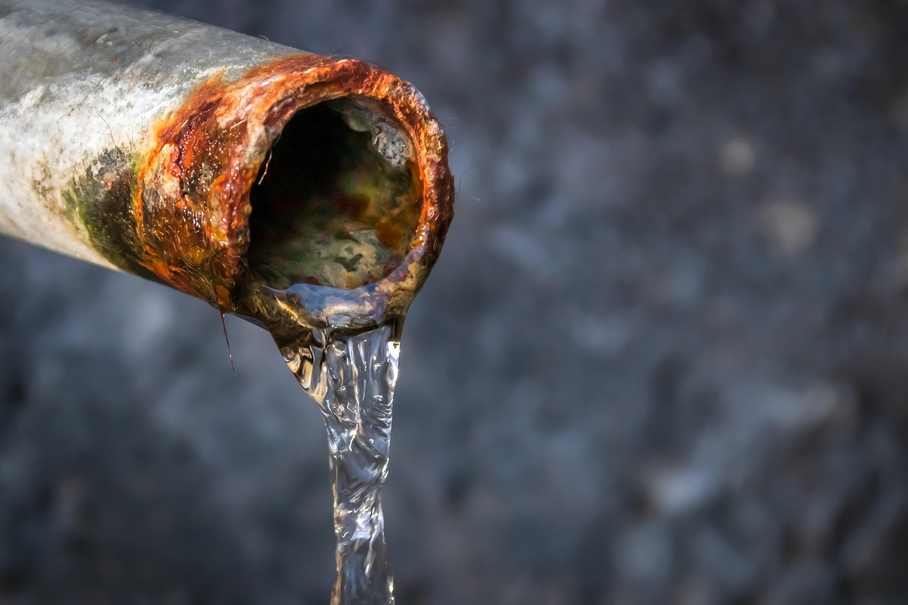 Rusty pipe leaking water, close-up of pipe with water dripping out.