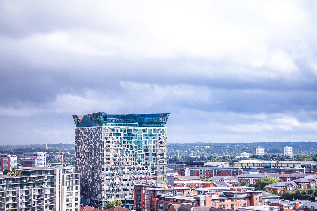 Modern cityscape with a distinctive high-rise building under cloudy sky.