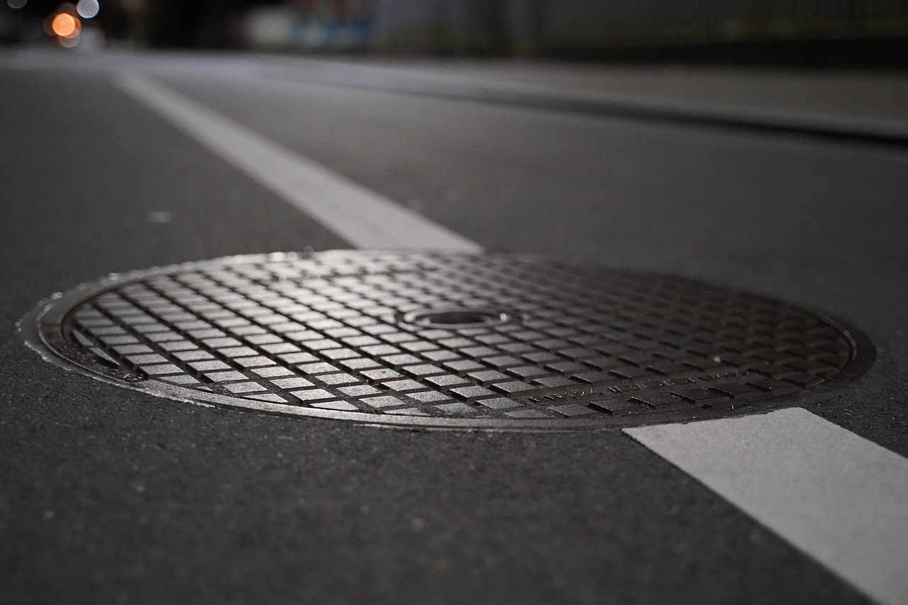 Close-up of a manhole cover on a city street with white road markings.