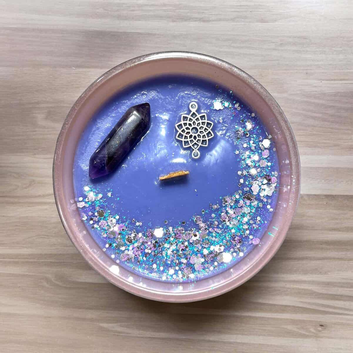 Blue candle with crystals, charm, and glitter for relaxation and meditation.