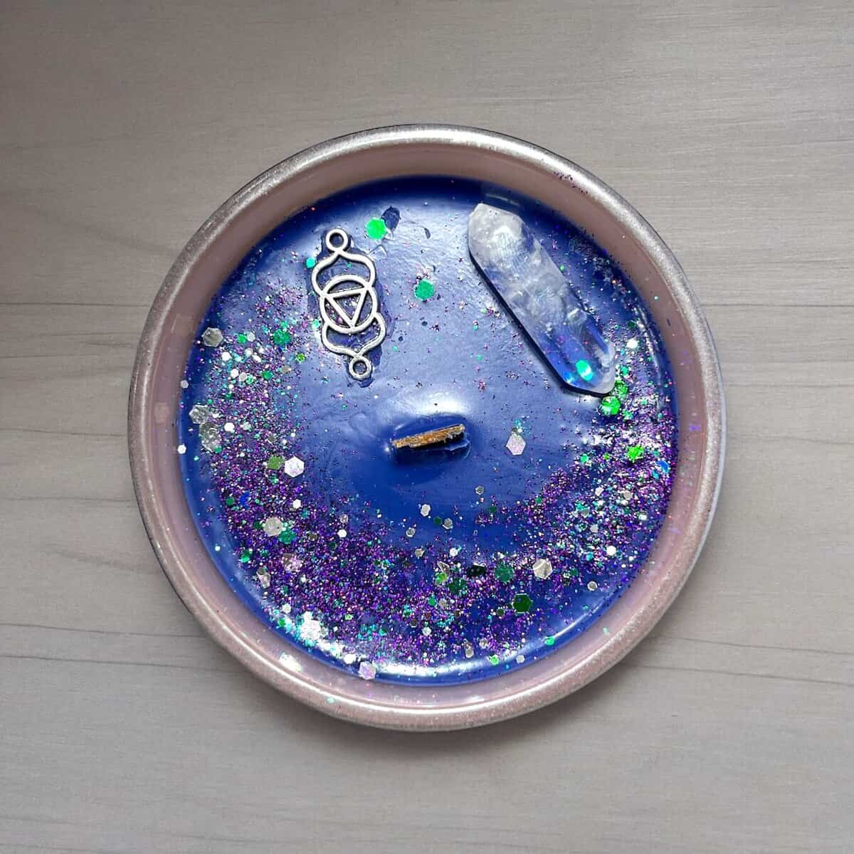 Grounding candle with glitter and crystal for root chakra meditation.