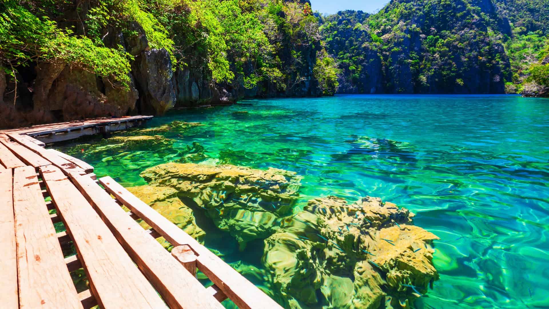 Clear turquoise lagoon with wooden boardwalk and limestone cliffs